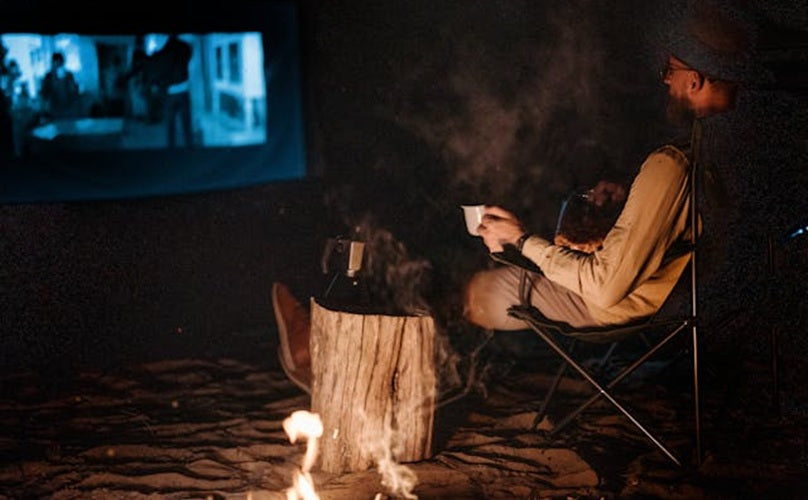 Man watching movie in wilderness at night